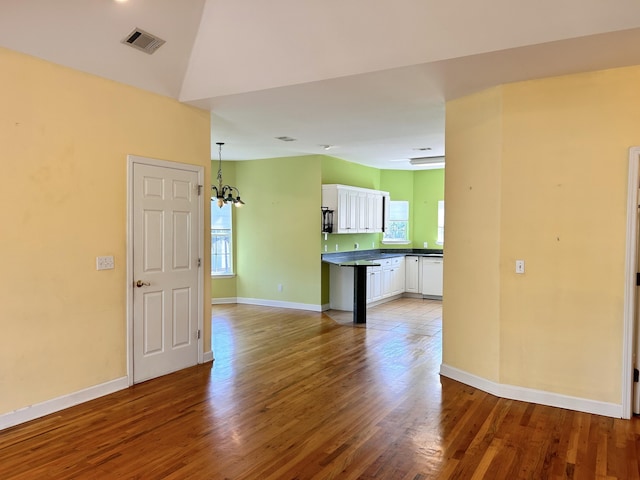 interior space featuring hardwood / wood-style flooring, lofted ceiling, and a notable chandelier