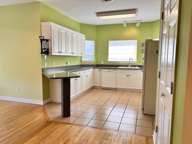 kitchen featuring white appliances, light tile patterned floors, sink, and white cabinets