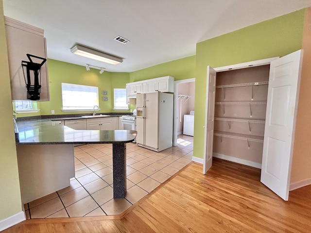 kitchen with sink, white appliances, light hardwood / wood-style flooring, white cabinets, and kitchen peninsula