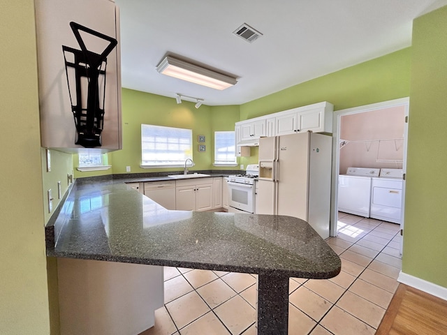 kitchen featuring washing machine and clothes dryer, white cabinetry, light tile patterned floors, kitchen peninsula, and white appliances