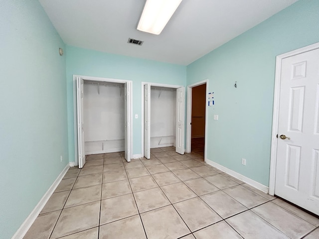 unfurnished bedroom featuring multiple closets and light tile patterned flooring