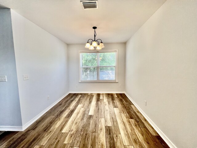 unfurnished dining area with hardwood / wood-style floors and a chandelier