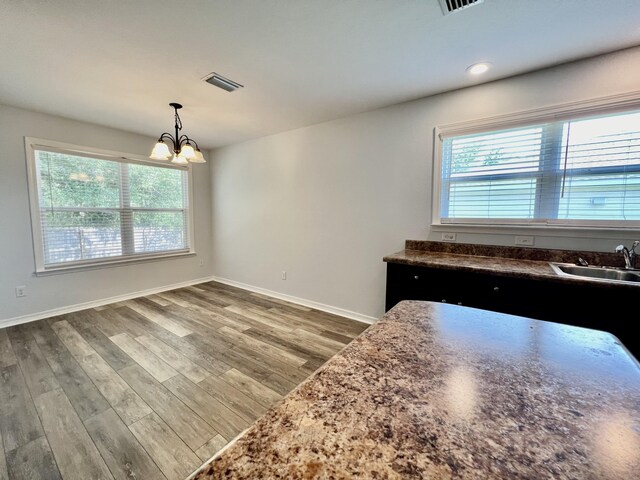 kitchen featuring hardwood / wood-style flooring, sink, an inviting chandelier, and decorative light fixtures