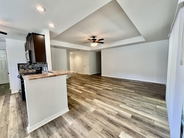 kitchen with black range oven, dark brown cabinets, light wood-type flooring, a raised ceiling, and ceiling fan