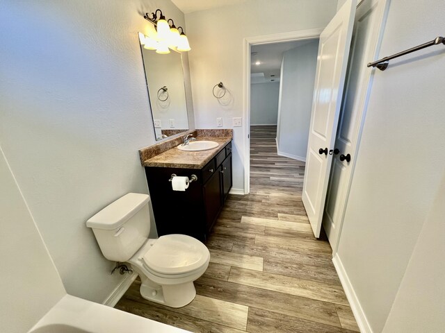 bathroom featuring wood-type flooring, toilet, and vanity