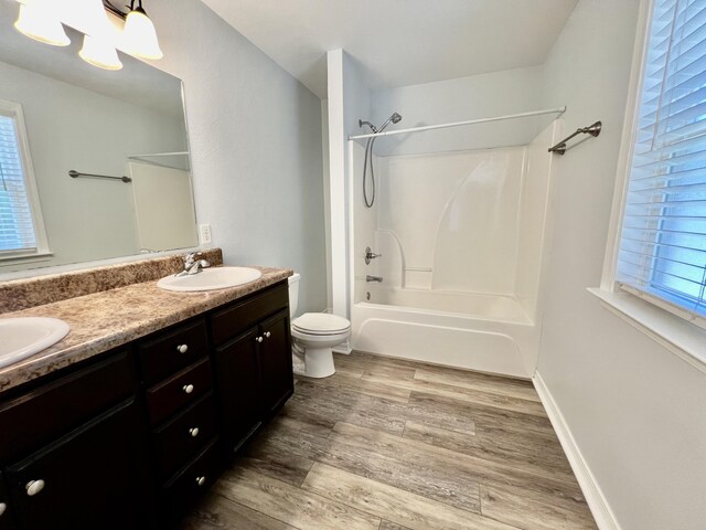 full bathroom featuring toilet, bathtub / shower combination, wood-type flooring, vanity, and a wealth of natural light