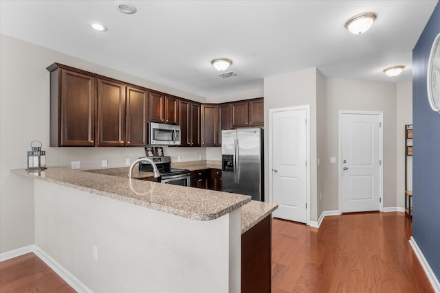 kitchen featuring sink, appliances with stainless steel finishes, dark brown cabinetry, dark hardwood / wood-style flooring, and kitchen peninsula