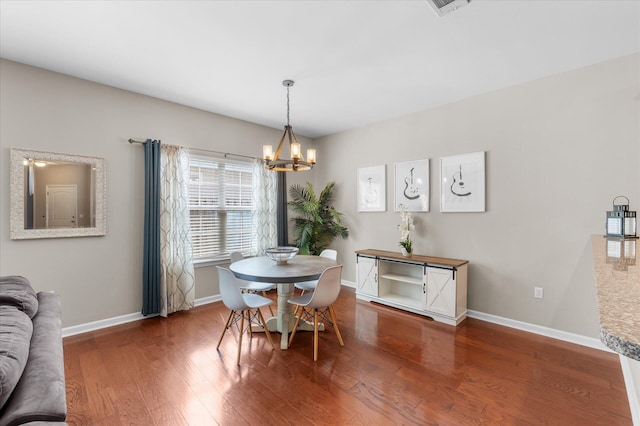 dining space featuring hardwood / wood-style flooring and a chandelier