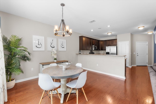 dining area featuring hardwood / wood-style flooring, sink, and a notable chandelier