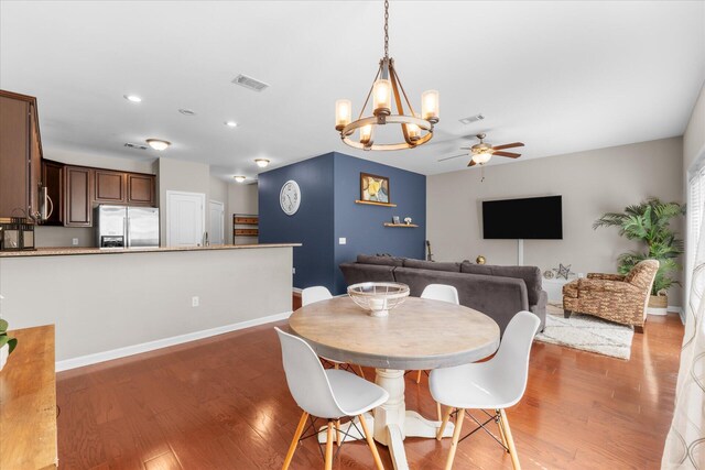 dining space with ceiling fan with notable chandelier and wood-type flooring