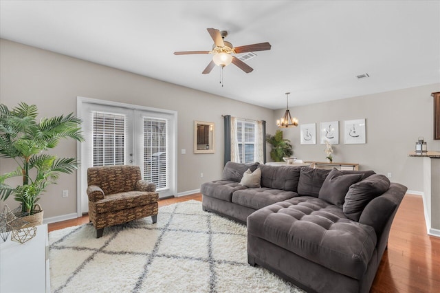 living room with ceiling fan with notable chandelier, french doors, and wood-type flooring