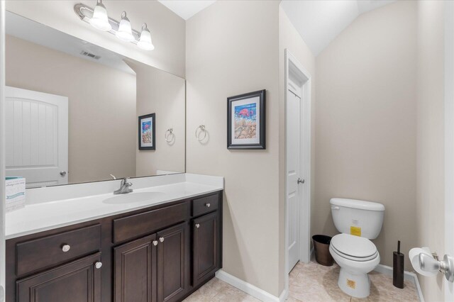 bathroom featuring tile patterned floors, vanity, lofted ceiling, and toilet