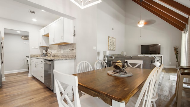 dining room featuring light hardwood / wood-style floors, high vaulted ceiling, and sink