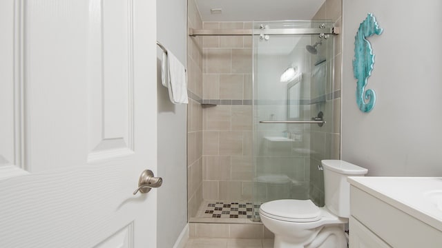 bathroom with tile patterned flooring, a shower with door, toilet, and vanity