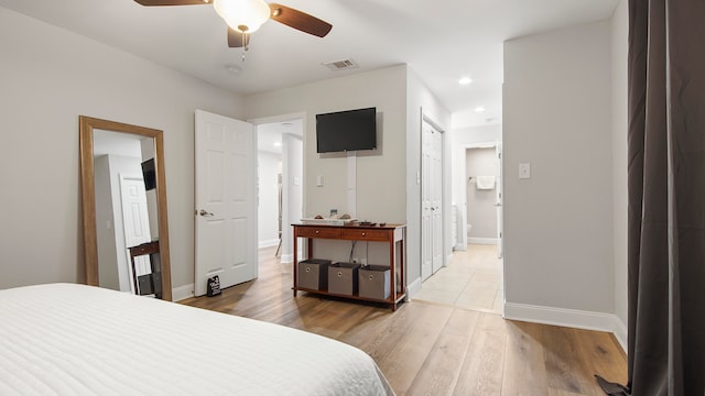 bedroom with ceiling fan, connected bathroom, and hardwood / wood-style floors