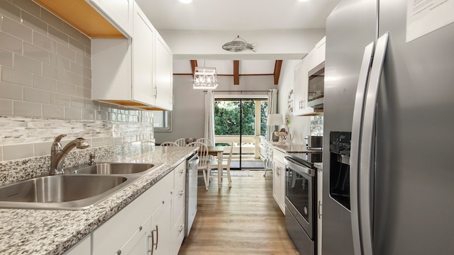 kitchen featuring light wood-type flooring, tasteful backsplash, white cabinets, sink, and stainless steel appliances