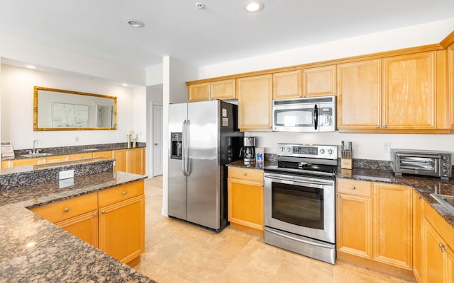 kitchen with dark stone countertops, light tile patterned flooring, and stainless steel appliances