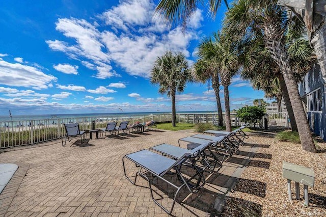 view of patio / terrace featuring a water view and a beach view