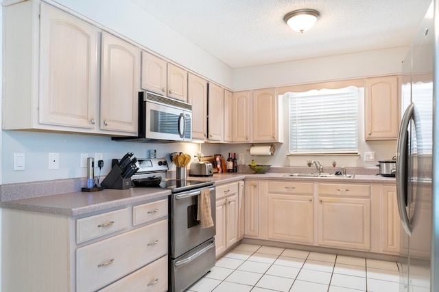 kitchen with sink, light brown cabinetry, light tile patterned floors, and stainless steel appliances