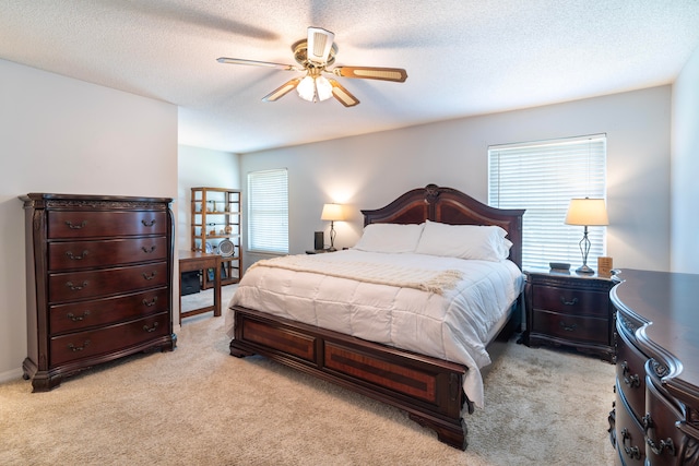 bedroom featuring light colored carpet, a textured ceiling, and ceiling fan