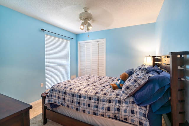 carpeted bedroom with ceiling fan, a closet, and a textured ceiling