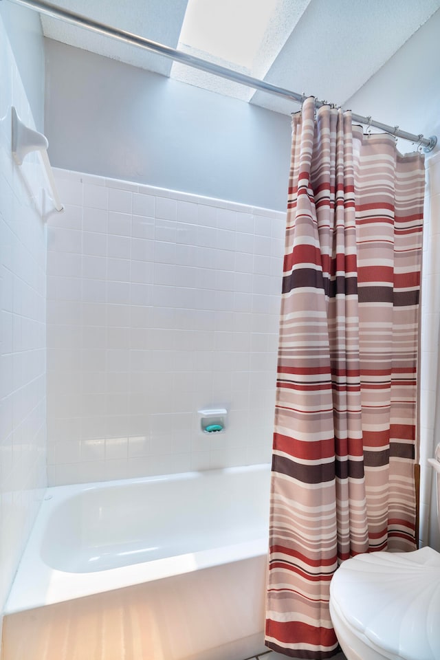 bathroom featuring a textured ceiling, toilet, and shower / tub combo