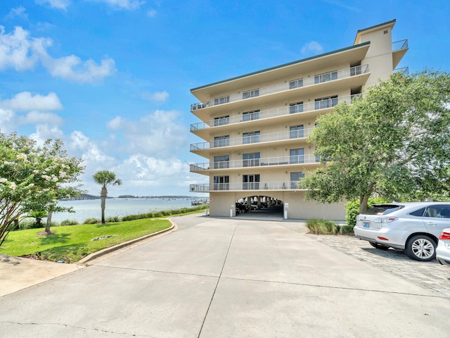 view of property featuring driveway, a carport, and a water view