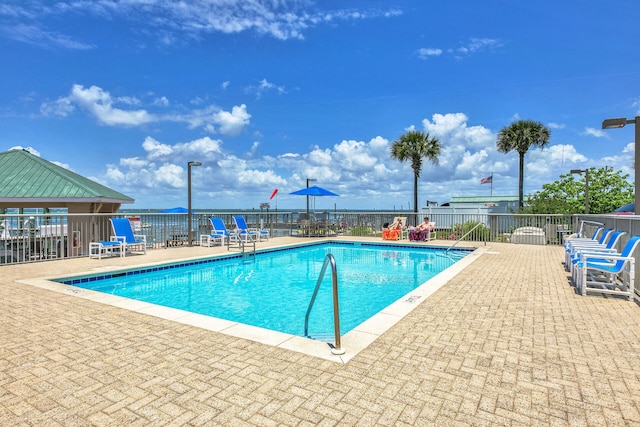 community pool with a patio area and fence