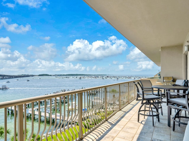 balcony with a water view and outdoor dining area