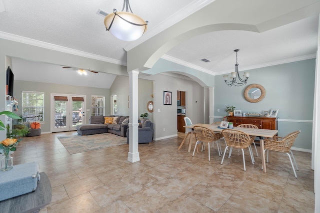 tiled dining space with ornamental molding, french doors, a chandelier, a textured ceiling, and decorative columns