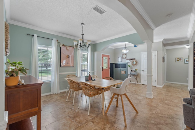 tiled dining area with a textured ceiling, decorative columns, a chandelier, and ornamental molding