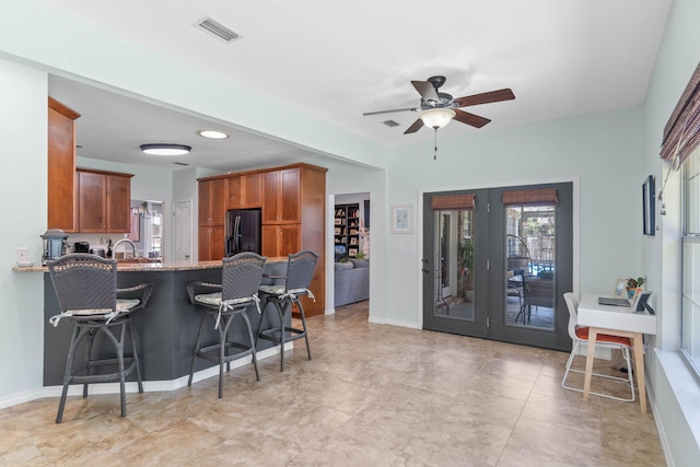 kitchen featuring ceiling fan, black refrigerator, and light tile patterned floors