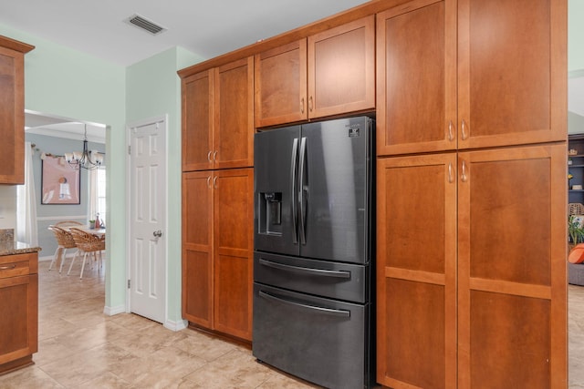 kitchen with a notable chandelier, light tile patterned floors, light stone countertops, and stainless steel refrigerator with ice dispenser