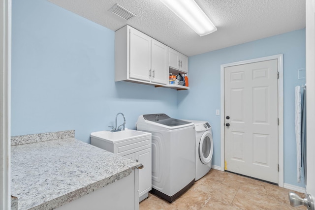 washroom featuring light tile patterned floors, sink, cabinets, a textured ceiling, and washer and dryer