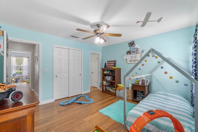 bedroom with ceiling fan, hardwood / wood-style flooring, a closet, and a textured ceiling