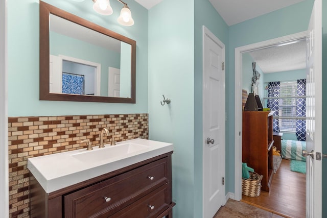 bathroom featuring hardwood / wood-style flooring, tasteful backsplash, a textured ceiling, and vanity