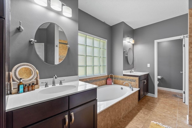 bathroom featuring a bathing tub, double vanity, tile patterned flooring, and a textured ceiling