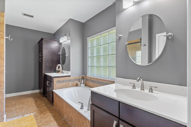 bathroom with tile patterned flooring, a bathtub, double sink vanity, and a textured ceiling