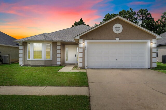 view of front of house with a lawn, a garage, and cooling unit