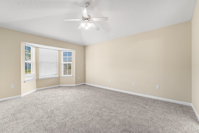 carpeted spare room with a textured ceiling, vaulted ceiling, and ceiling fan