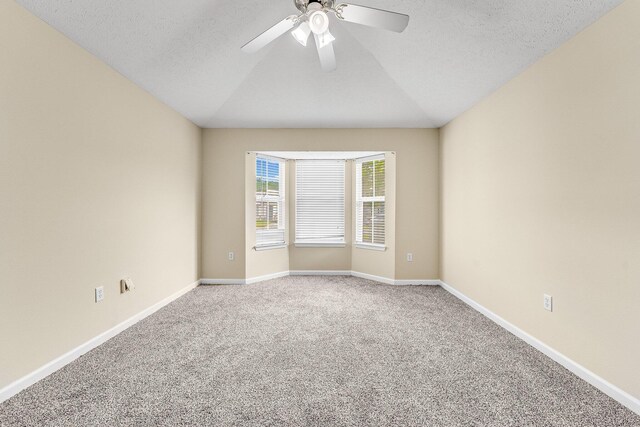 unfurnished room featuring vaulted ceiling, carpet, and a textured ceiling