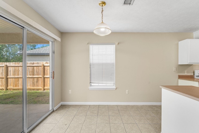 unfurnished dining area featuring a textured ceiling and light tile patterned flooring