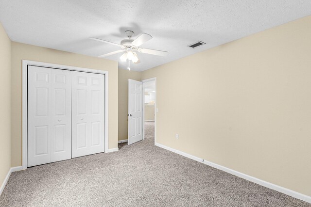 unfurnished bedroom with ceiling fan, carpet flooring, a textured ceiling, and a closet