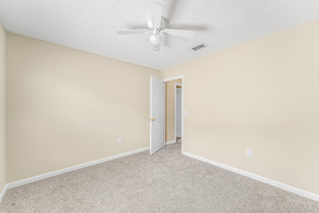 empty room featuring light carpet, ceiling fan, and a textured ceiling