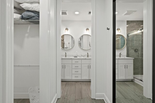 bathroom featuring wood-type flooring, double sink vanity, and a shower with door