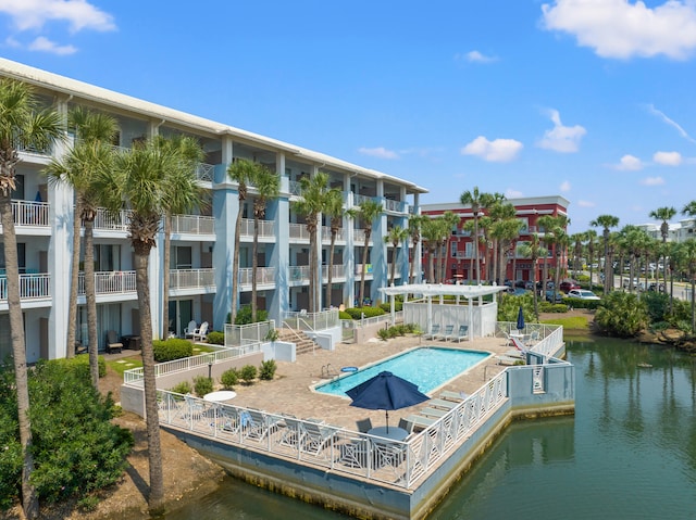 exterior space with a balcony, a community pool, and a water view