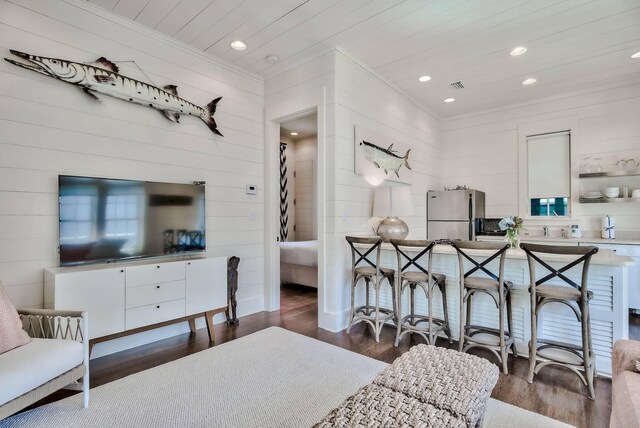 living room featuring crown molding, dark wood-type flooring, and wood walls