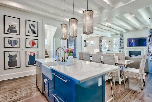 kitchen featuring beam ceiling, dark hardwood / wood-style flooring, a kitchen island with sink, and blue cabinetry