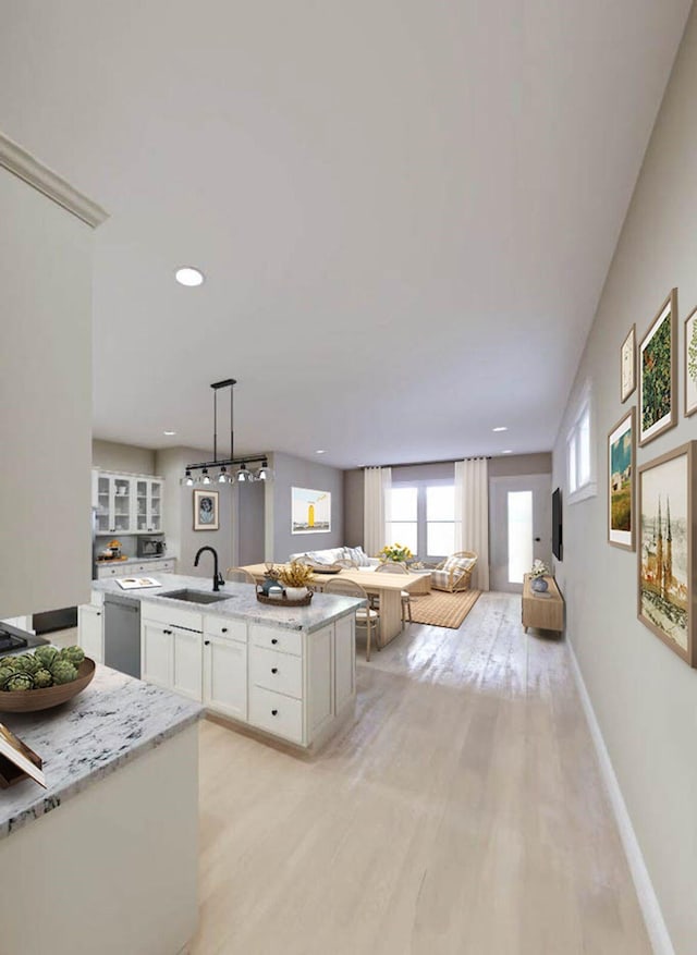 kitchen featuring white cabinets, dishwasher, open floor plan, light wood-style floors, and a sink