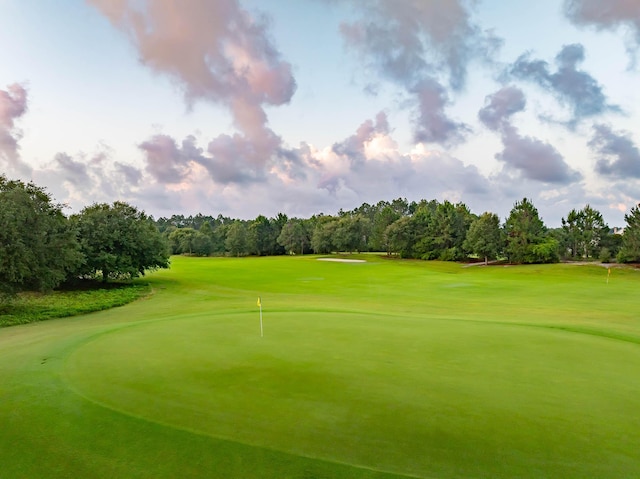 surrounding community with view of golf course and a lawn